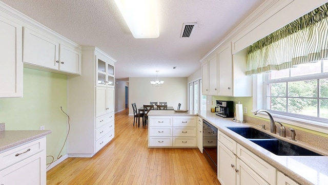 kitchen featuring white cabinetry, a sink, visible vents, black dishwasher, and a peninsula