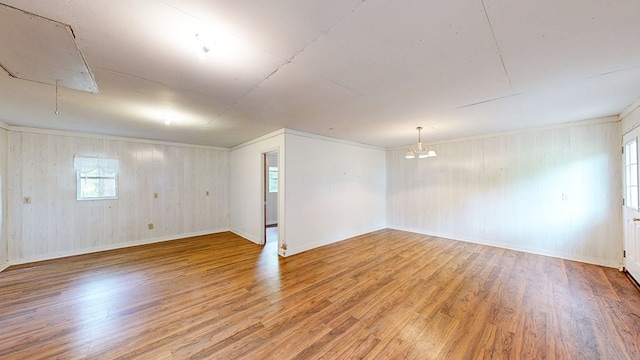 basement featuring wood walls, wood finished floors, a chandelier, and baseboards