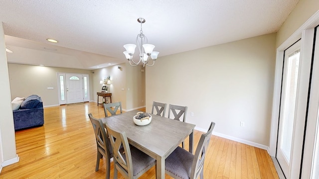 dining room with a notable chandelier, recessed lighting, light wood finished floors, and baseboards