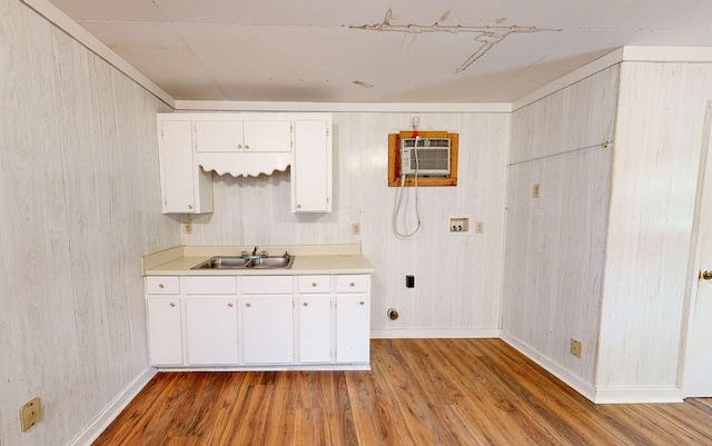 kitchen featuring wood finished floors, a wall unit AC, white cabinets, and light countertops