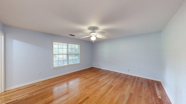 spare room with light wood finished floors, visible vents, ceiling fan, and baseboards
