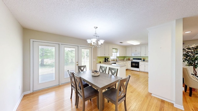 dining area with a textured ceiling, french doors, light wood-type flooring, and a notable chandelier