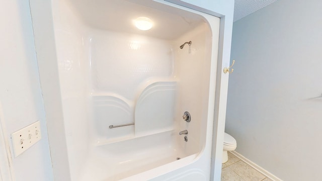 bathroom with tile patterned floors, toilet, tub / shower combination, and baseboards
