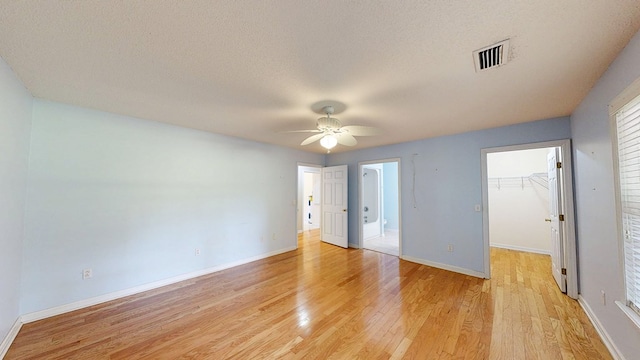 unfurnished bedroom with visible vents, a closet, baseboards, light wood-type flooring, and a spacious closet