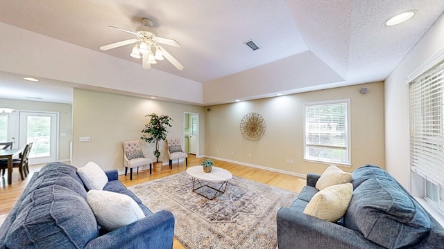 living area featuring light wood finished floors, a ceiling fan, visible vents, and baseboards