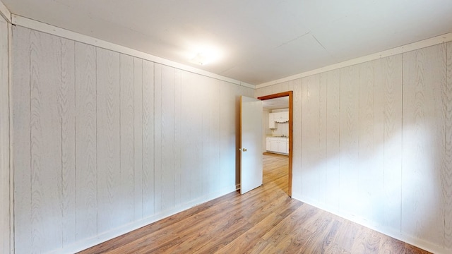 empty room with wooden walls, wood finished floors, and baseboards