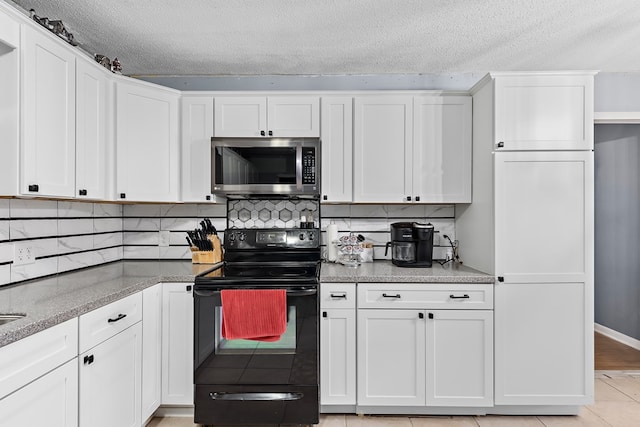 kitchen with decorative backsplash, light tile patterned floors, white cabinetry, and black range with electric stovetop