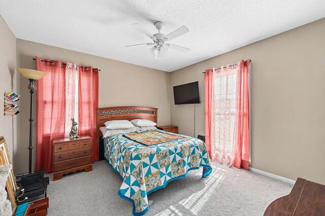 carpeted bedroom with a textured ceiling, ceiling fan, and baseboards