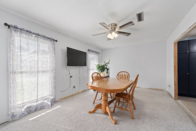 dining area featuring ceiling fan, light carpet, plenty of natural light, and visible vents