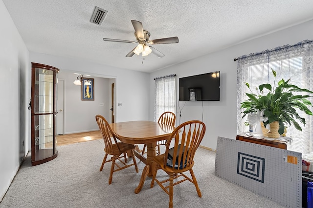 dining room with a textured ceiling, a ceiling fan, visible vents, and a healthy amount of sunlight