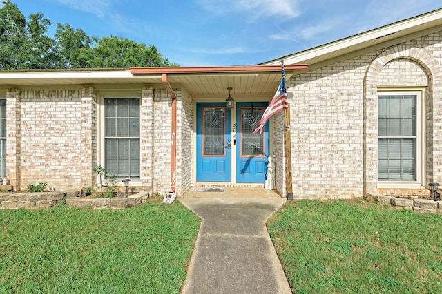 property entrance with brick siding and a lawn