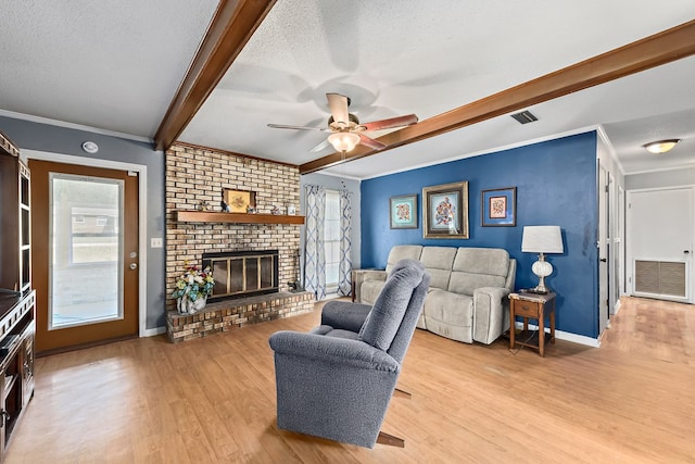 living area with light wood finished floors, visible vents, beamed ceiling, a textured ceiling, and a fireplace