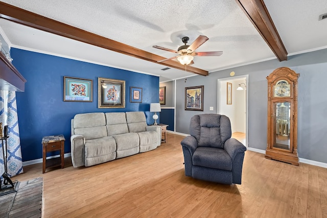 living area with beam ceiling, visible vents, light wood-style flooring, a textured ceiling, and baseboards