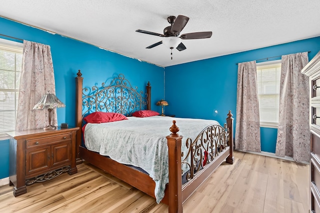 bedroom with light wood-type flooring, a ceiling fan, and a textured ceiling