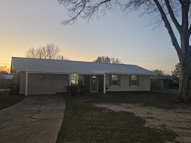 ranch-style home featuring driveway and metal roof