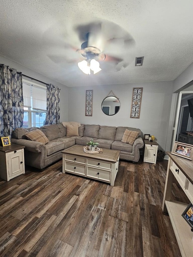 living room featuring visible vents, a textured ceiling, ceiling fan, and dark wood-style flooring