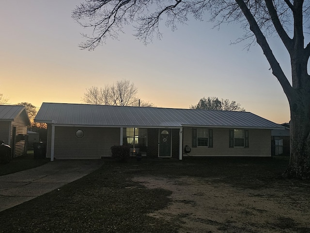 single story home with driveway and metal roof