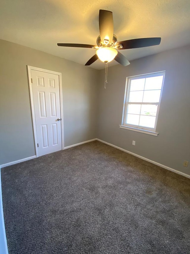 empty room with ceiling fan, dark carpet, and a textured ceiling