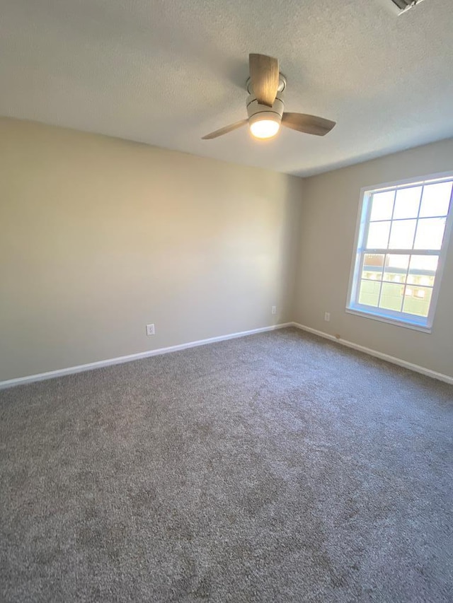 empty room with dark colored carpet, ceiling fan, and a textured ceiling