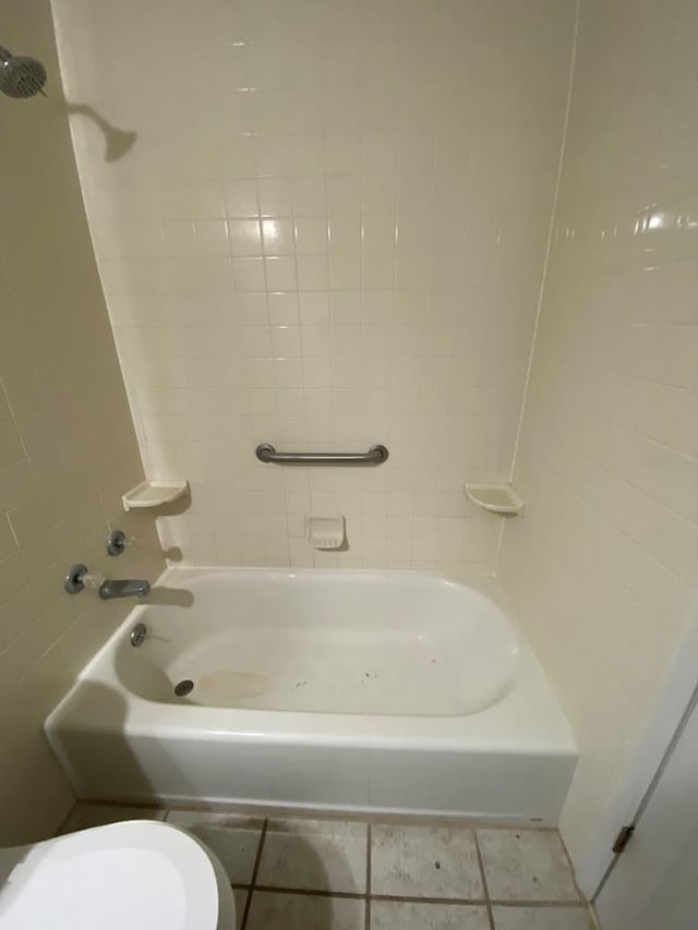 bathroom with tile patterned flooring, tiled shower / bath, and toilet