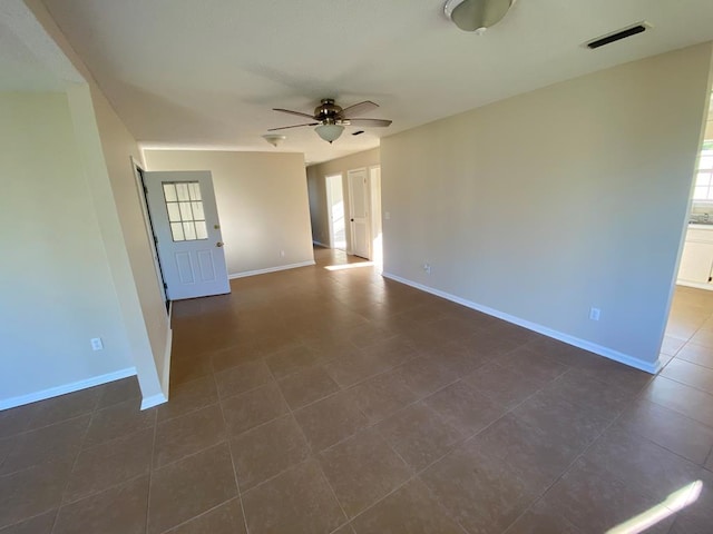 empty room featuring ceiling fan and dark tile patterned flooring