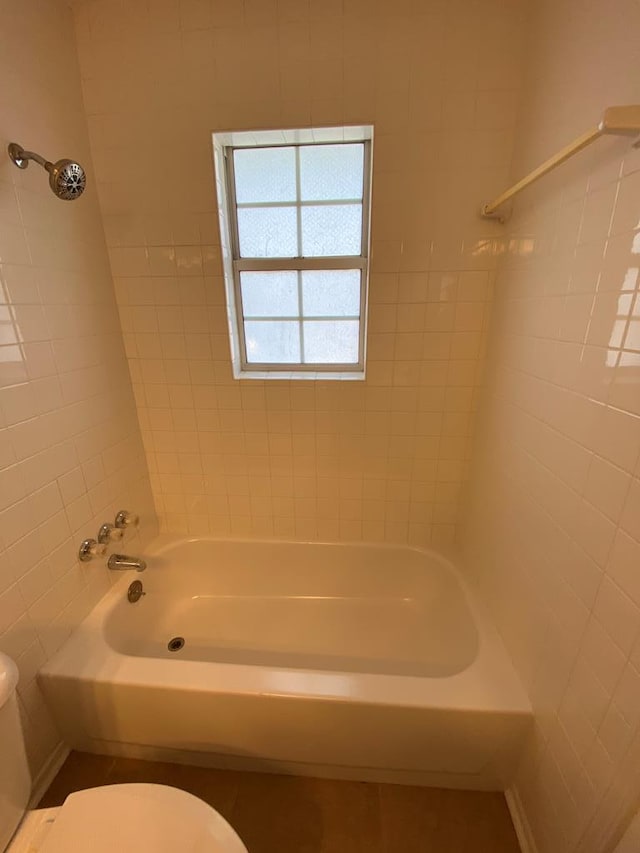 bathroom with toilet and tiled shower / bath