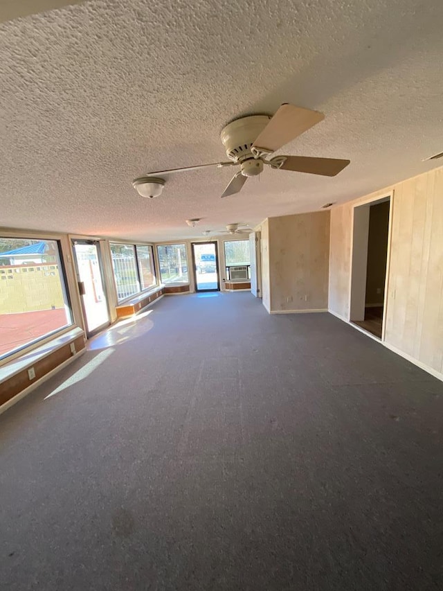 unfurnished room with carpet, a textured ceiling, cooling unit, ceiling fan, and wooden walls