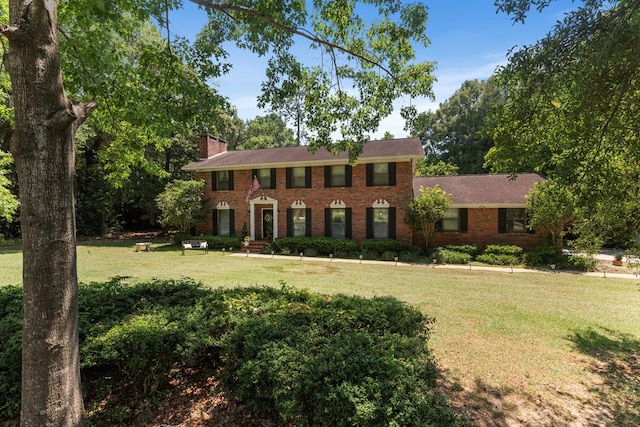 colonial-style house featuring a front yard