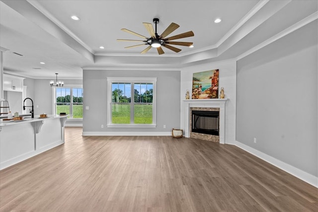 45 County Road 711, Enterprise, AL 36330 - unfurnished living room featuring a tray ceiling, light wood-style flooring, a fireplace, a chandelier, and crown molding