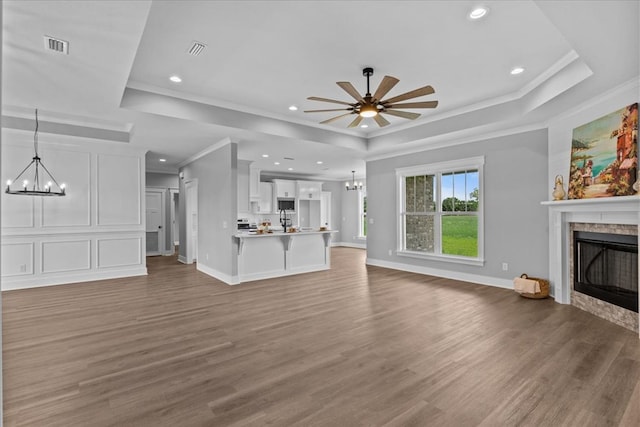 45 County Road 711, Enterprise, AL 36330 - unfurnished living room featuring a chandelier, a tray ceiling, ornamental molding, a stone fireplace, and wood finished floors