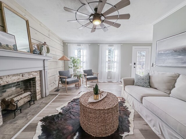 living room with crown molding, ceiling fan, light hardwood / wood-style floors, and a textured ceiling