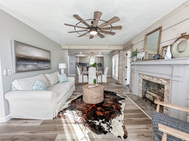 living room with crown molding, ceiling fan, a textured ceiling, and light hardwood / wood-style floors