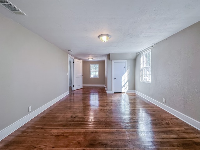 empty room with dark hardwood / wood-style floors and a textured ceiling