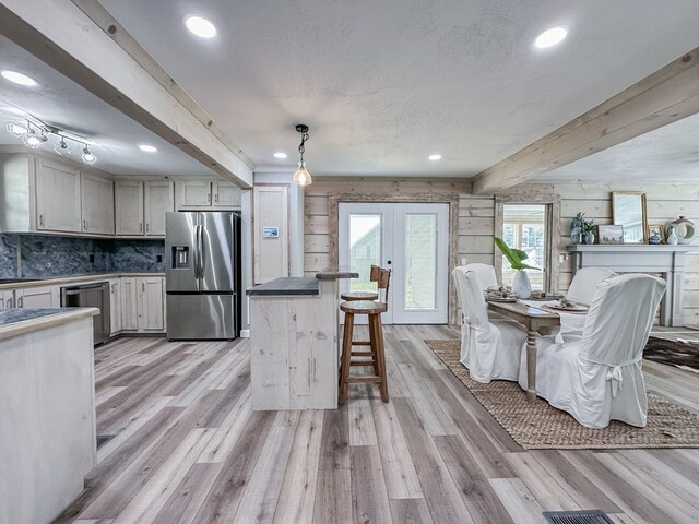 kitchen featuring pendant lighting, stainless steel refrigerator with ice dispenser, light hardwood / wood-style floors, french doors, and beamed ceiling