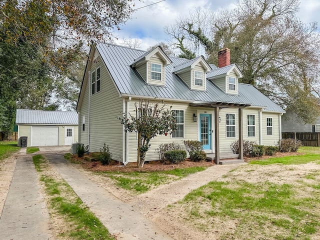 cape cod-style house featuring a garage, an outbuilding, and central air condition unit