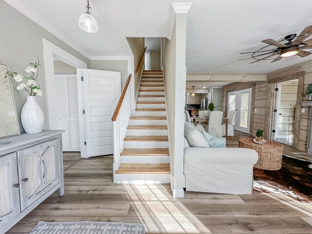 stairway with wood-type flooring, ornamental molding, and ceiling fan