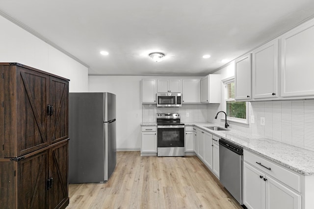1571 Denton Rd, Dothan, AL 36303 - kitchen featuring stainless steel appliances, light wood-style flooring, tasteful backsplash, light stone countertops, and white cabinetry
