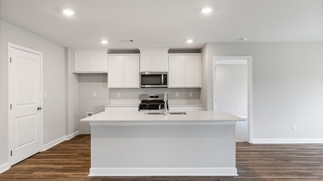 kitchen with white cabinets, an island with sink, dark wood-style flooring, stainless steel appliances, and a sink