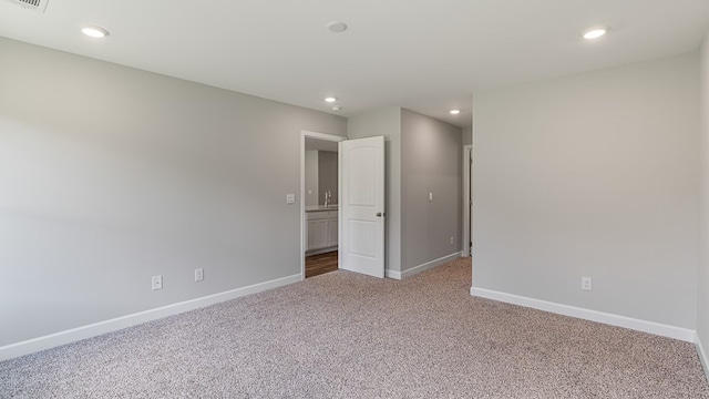 empty room featuring carpet floors, visible vents, baseboards, and recessed lighting