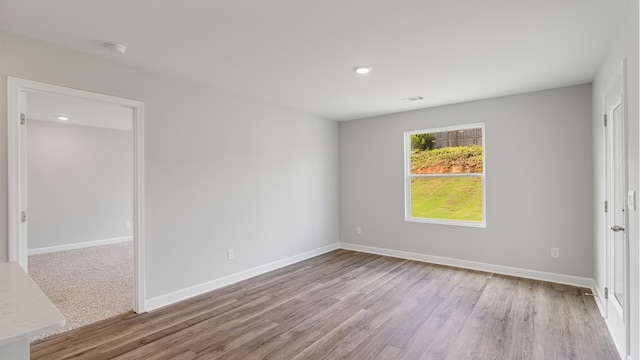 spare room with visible vents, baseboards, and wood finished floors