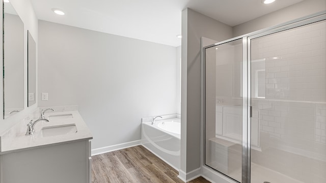 bathroom with a stall shower, wood finished floors, a sink, and a bath