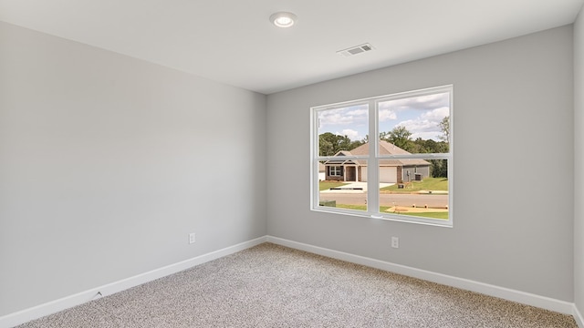 empty room featuring light carpet, visible vents, and baseboards