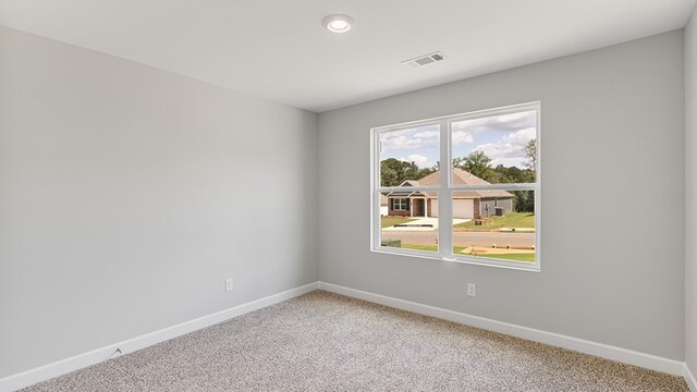 spare room with baseboards, visible vents, and light colored carpet