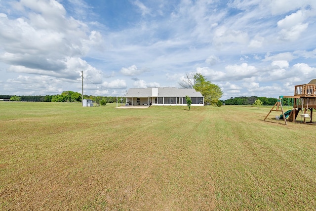 view of yard featuring an outdoor structure, a sunroom, and playground community