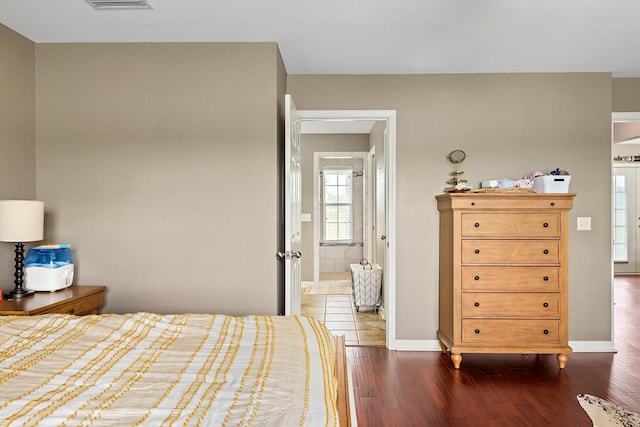 unfurnished bedroom featuring visible vents, baseboards, ensuite bath, and dark wood finished floors