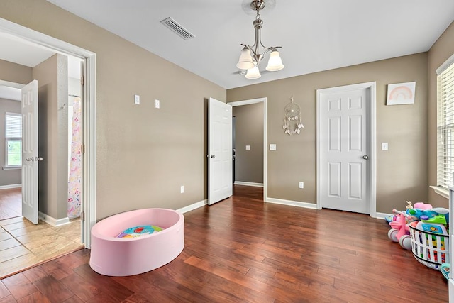 rec room featuring baseboards, wood-type flooring, a notable chandelier, and visible vents