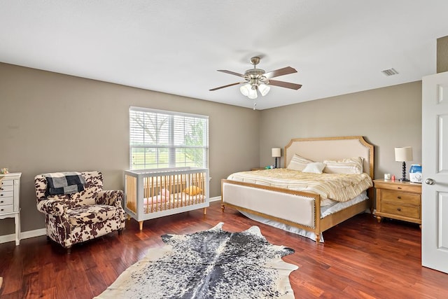 bedroom with ceiling fan, visible vents, baseboards, and wood finished floors