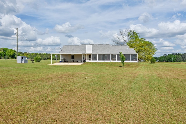 back of property featuring a sunroom, a storage shed, a yard, a patio area, and an outbuilding