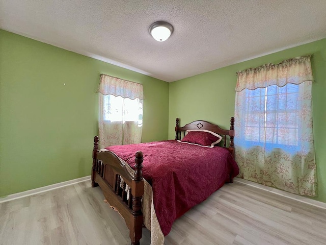 bedroom with baseboards, a textured ceiling, and wood finished floors