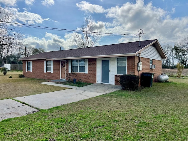 ranch-style house featuring driveway, cooling unit, roof with shingles, a front yard, and brick siding